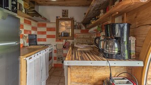 Eine kleine Küche mit Kühlschrank, Herd, Kaffeemaschine und Toaster.