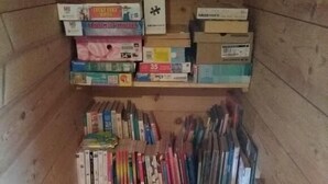 Ein Holzinnenraum mit Regalen, voll mit Büchern und Kisten.