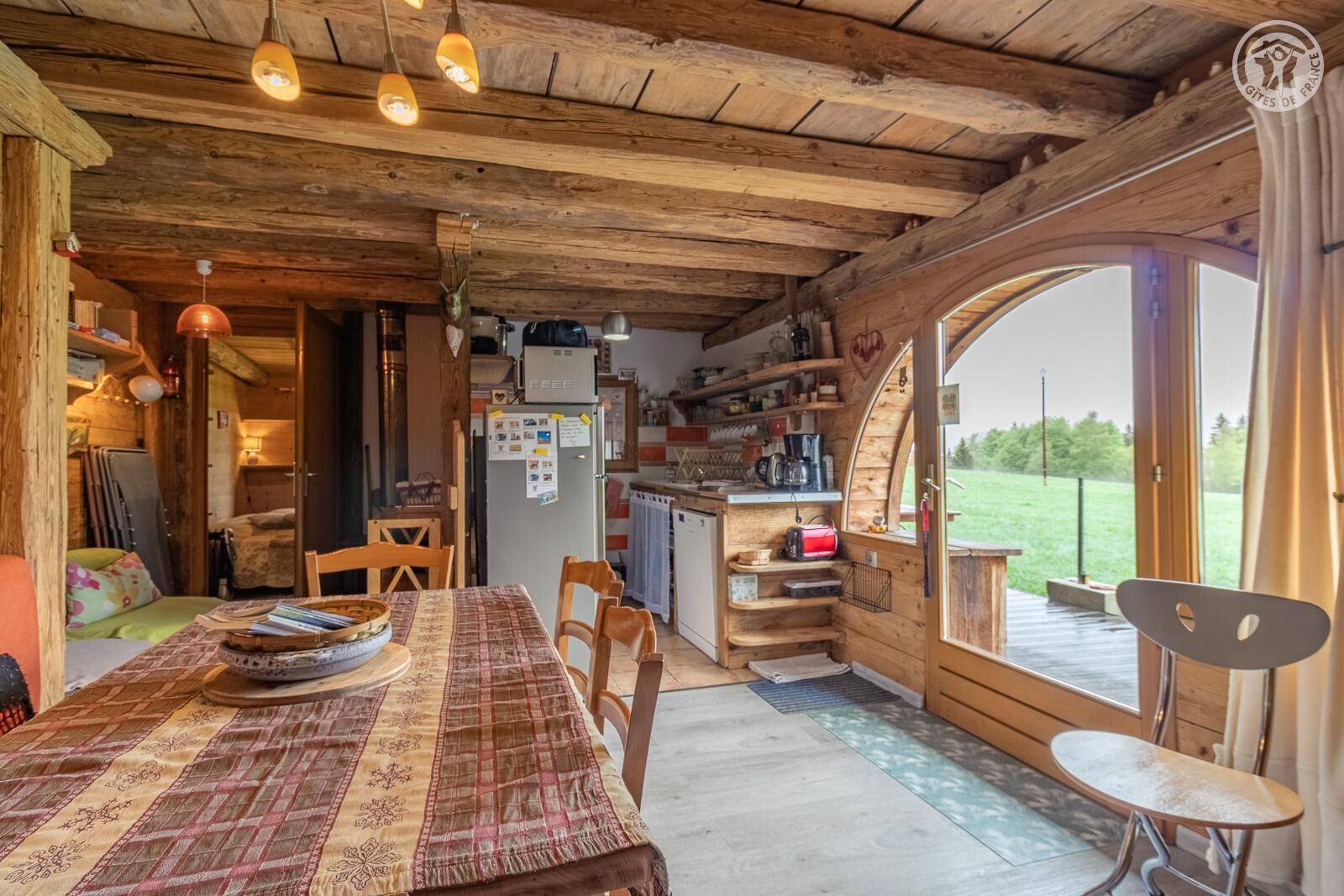 Un intérieur rustique en bois, comprenant un coin repas, une cuisine et de grandes fenêtres.
