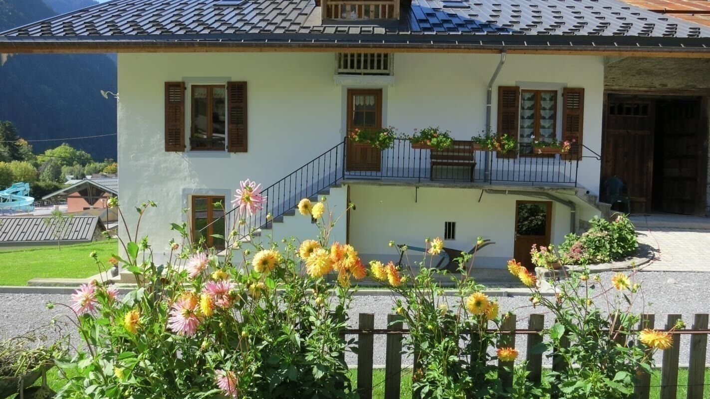 Une maison à deux étages avec un balcon, un escalier et une clôture en bois au premier plan.