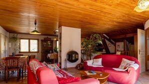 Una sala de estar acogedora con techo de madera, un sofá rojo, una mesa de centro de madera y una chimenea.