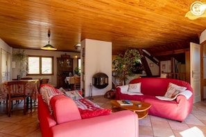 Un salon chaleureux avec un plafond en bois, un canapé rouge, une table basse en bois et une cheminée.