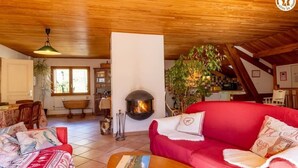 Una sala de estar acogedora con chimenea, sofá rojo y comedor con muebles de madera.