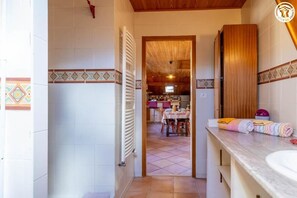 Une salle de bain avec un lavabo blanc, des meubles en bois et un sol carrelé.