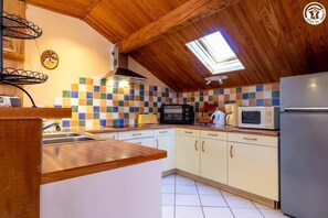 A kitchen with a sloped ceiling, a skylight, a tiled backsplash, and modern appliances.