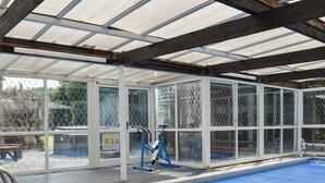 Una piscina interior con cerramiento de vidrio, suelo azul y una máquina de ejercicios azul.