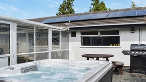 Una bañera de hidromasaje, una parrilla para barbacoa y paneles solares en el techo de una casa.