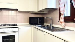 A kitchen with white cabinets, a gas stove, a microwave, and a sink. - RM11 - Senigallia, three-room apartment facing the sea (Senigallia)