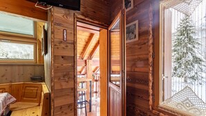 A wooden cabin interior with a sauna, a window with a view of snow-covered trees, and a television mounted on the wall. - LE VALLON - VALLOIRE (VALLOIRE)