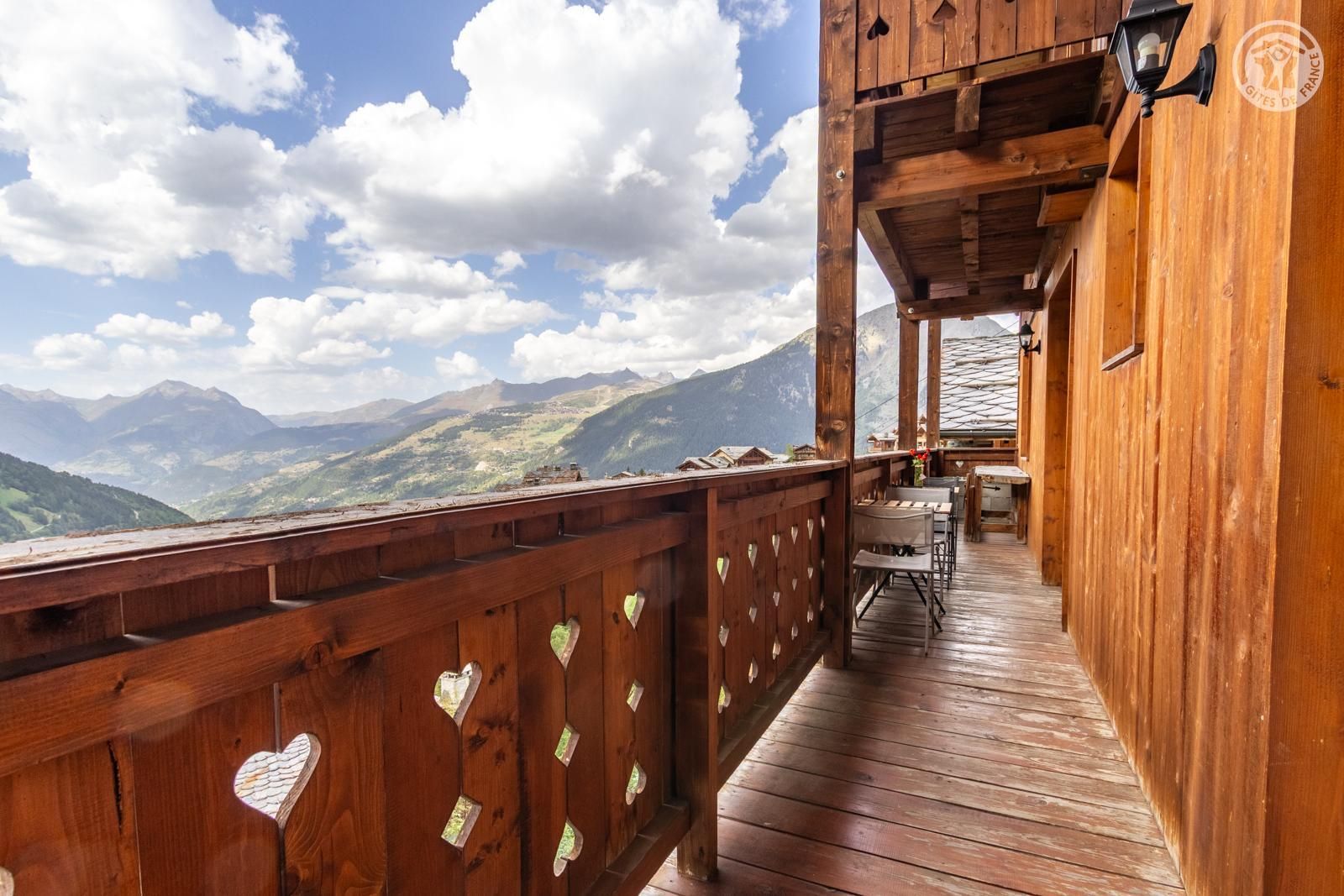 Eine Holterrasse mit herzförmigen Ausschnitten, die auf eine gebirgige Landschaft blickt.