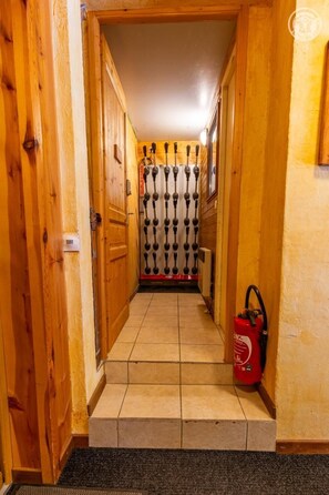 A hallway with wooden walls and a tiled floor leading to a door with a decorative metal gate. - Chalet l'Echaillon - Ormelune (SAINTE FOY TARENTAISE)