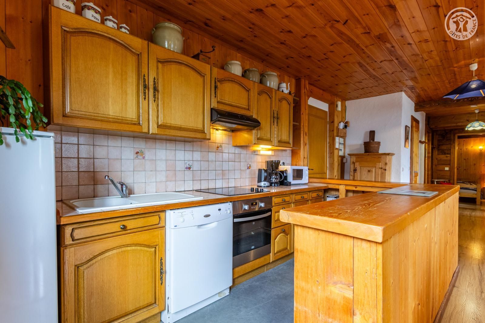 Eine Küche mit Holzschränken, einem Geschirrspüler, einer Mikrowelle und einer Kaffeemaschine.