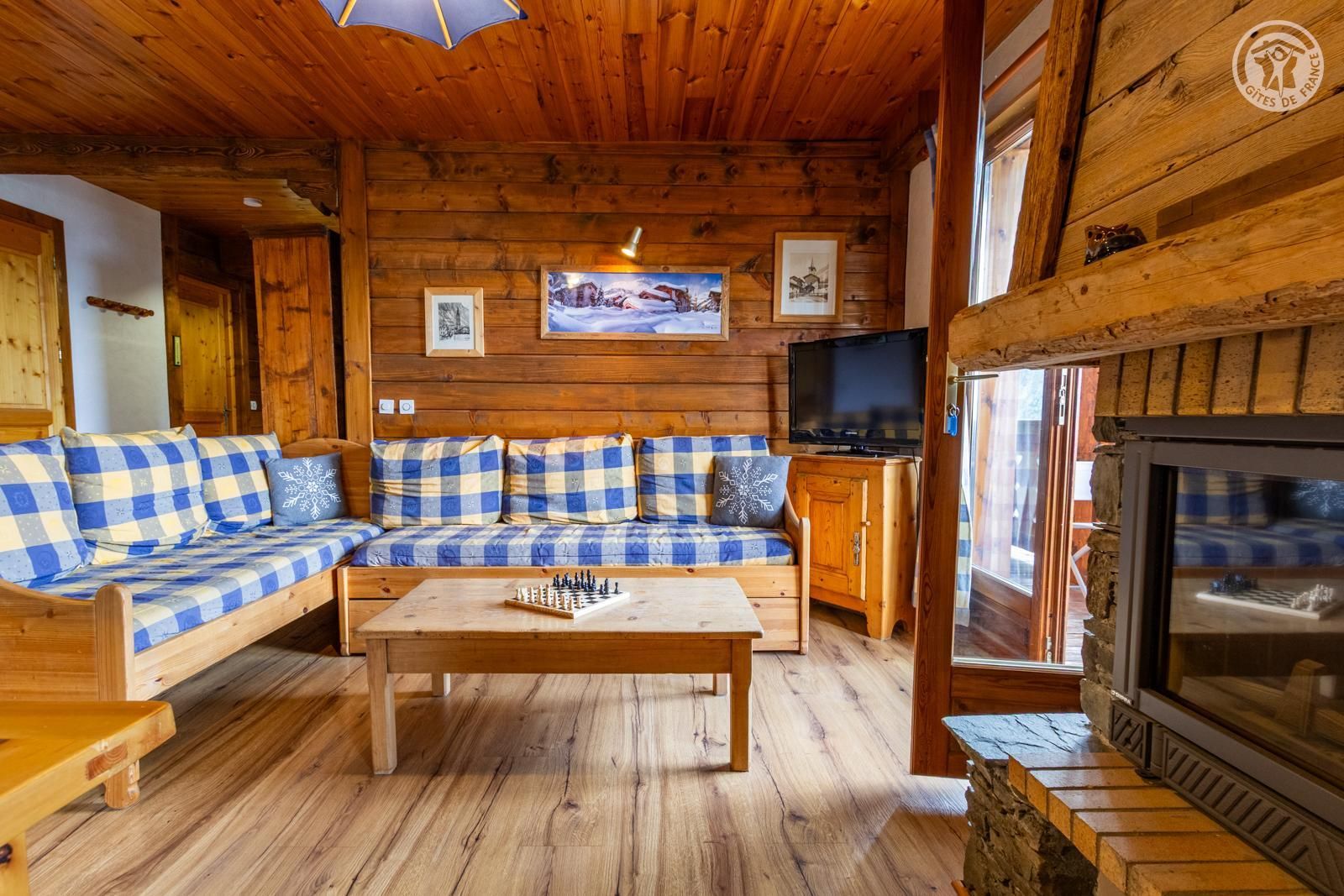 A cozy cabin interior with a checkered sofa, a wooden coffee table, and a fireplace.