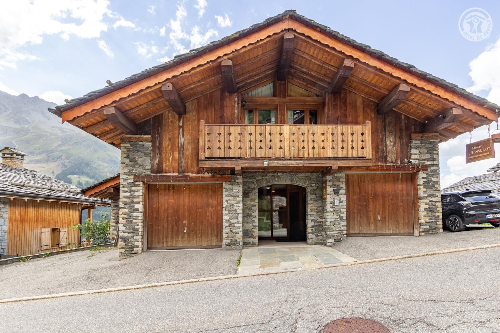 Een houten chalet met een balkon, stenen muren en een garage.