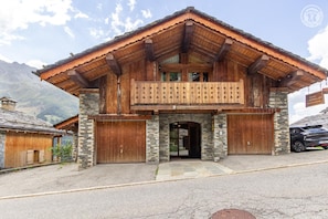 A wooden chalet with a balcony, stone walls, and a garage. - Chalet l'Echaillon - Ormelune (SAINTE FOY TARENTAISE)