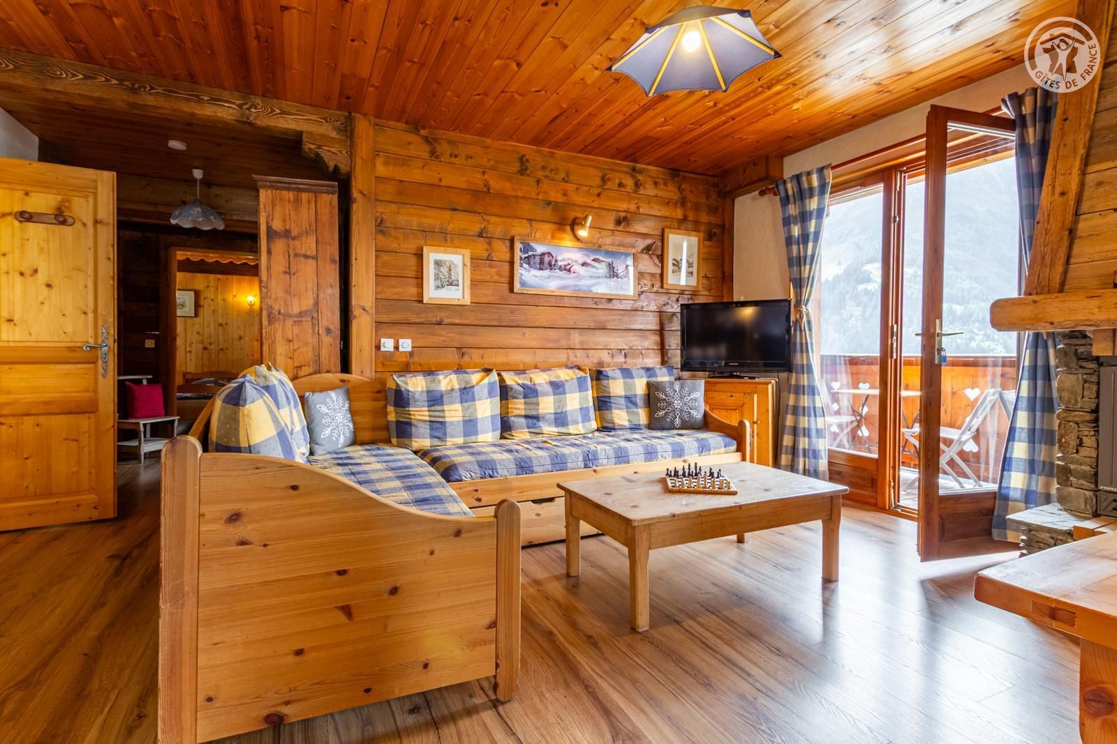 Un acogedor interior de cabaña de troncos con un sofá, un televisor y una chimenea.