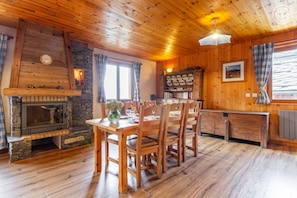 A wooden interior with a fireplace, dining table, chairs, and a stone wall. - Chalet l'Echaillon - Ormelune (SAINTE FOY TARENTAISE)