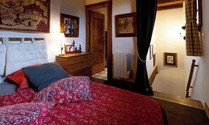 A bedroom with a bed, a dresser, and a door leading to another room.