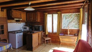 Una cocina tipo cabaña con armarios de madera, un refrigerador, un microondas y un comedor con mesa y sillas.