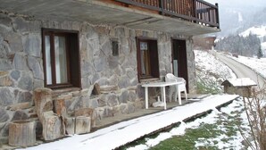 Un edificio de piedra con un balcón, una mesa y sillas afuera.