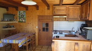 Un interior de madera con una mesa de comedor, armarios de madera, un salpicadero de cocina con azulejos y una pequeña isla.