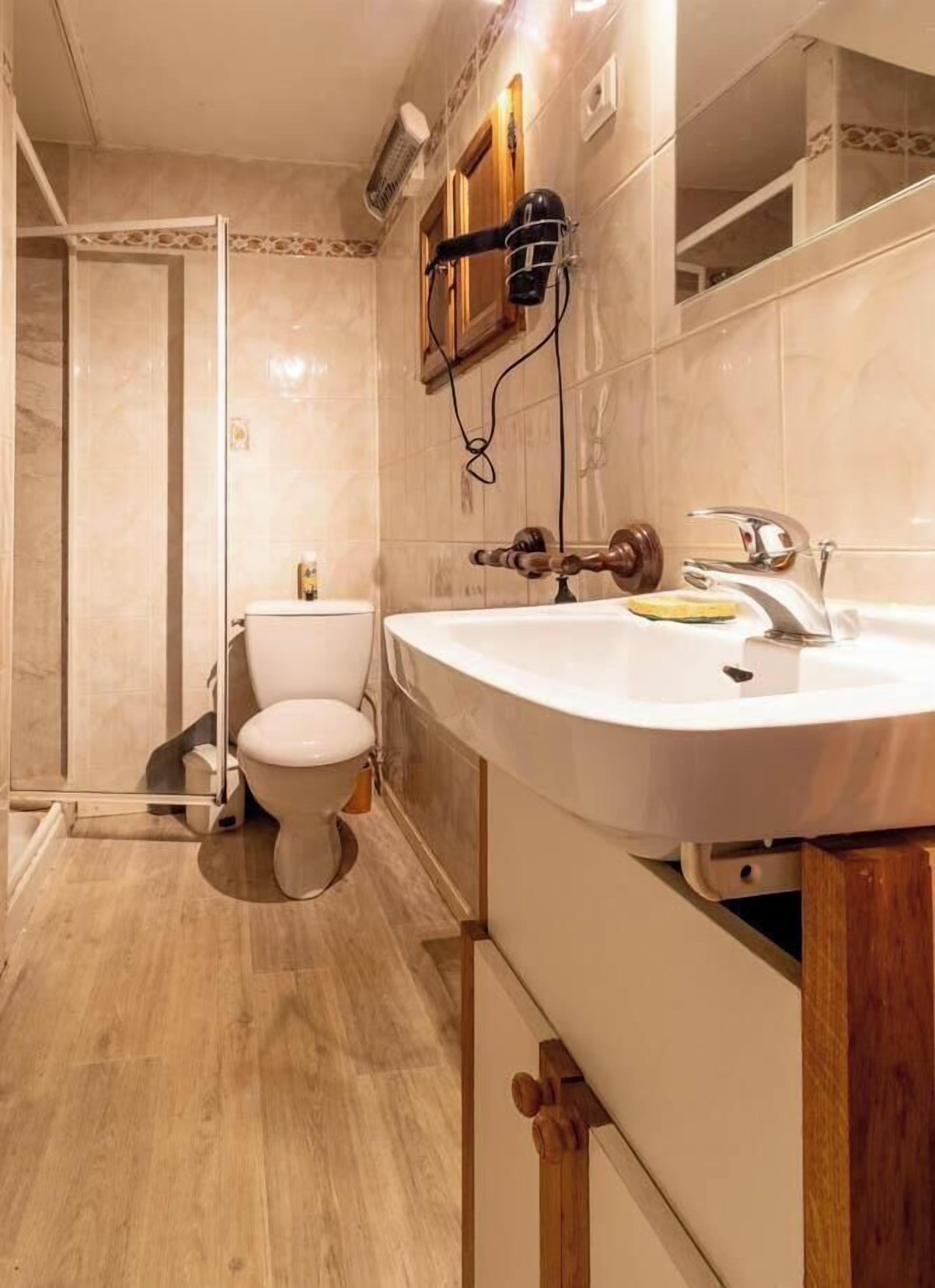 Une salle de bain comprenant des toilettes, un lavabo et un espace douche.