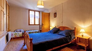A bedroom with a wooden bed, a nightstand, a window, and a door. - LE COLIBRI - BEAUFORT ARECHES (BEAUFORT ARECHES)