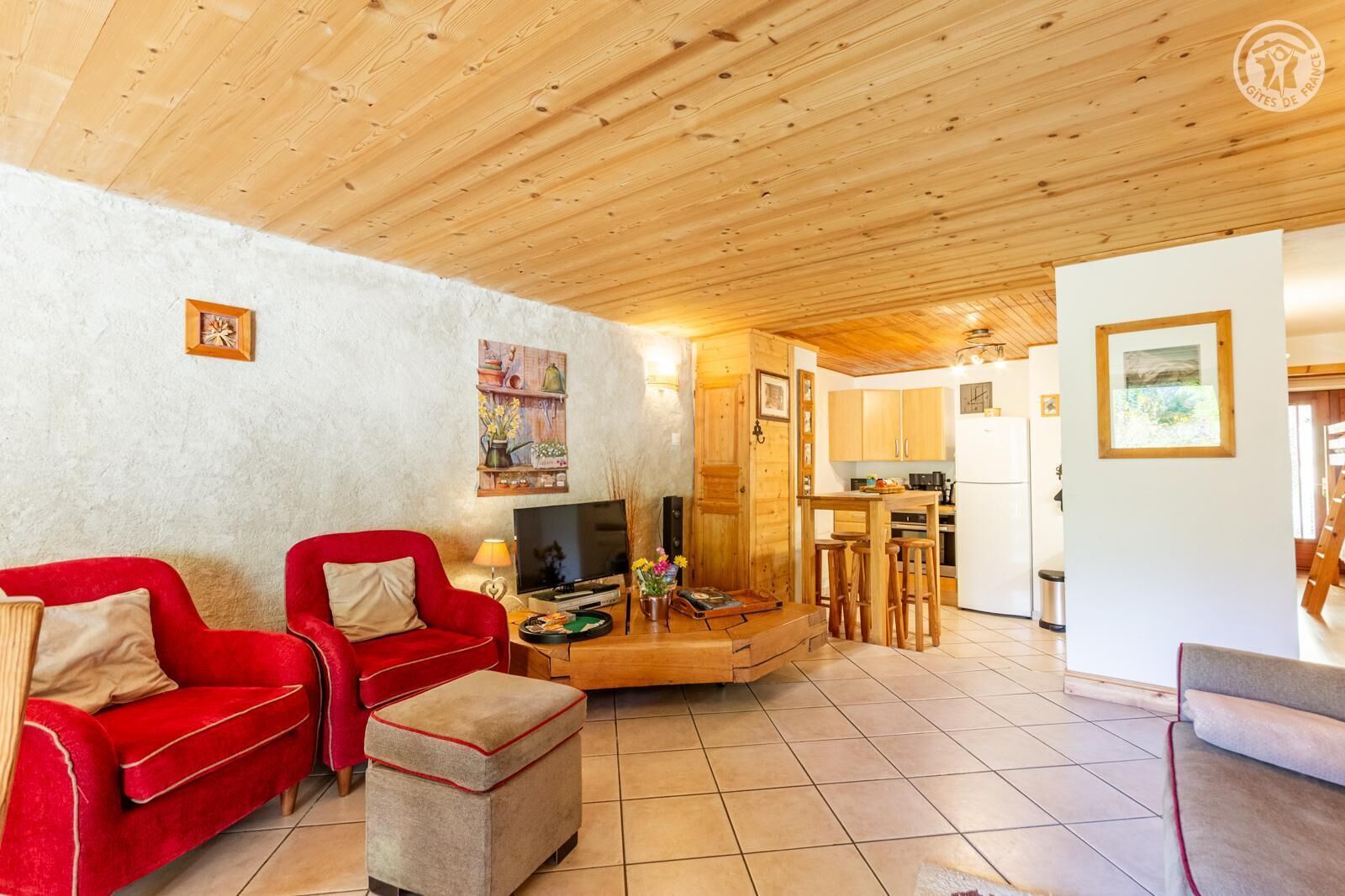 A cozy living room with a red sofa, a television, and a wooden dining area.