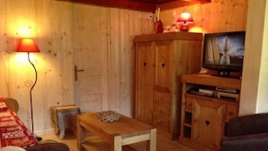 Un salon chaleureux avec des murs en bois, une télévision, une petite table et un canapé.