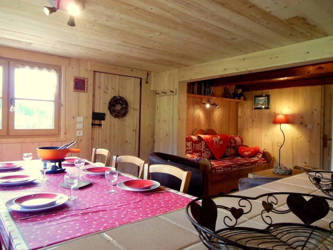 Interno di una baita in legno con zona pranzo, angolo relax e camino.
