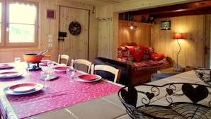 L’intérieur d’un chalet en bois comprend un coin repas, un espace salon confortable et une cheminée.