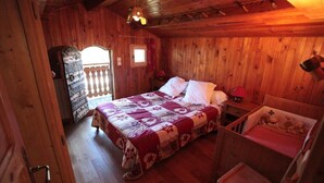 Une chambre dans une cabane en bois, avec un lit, une petite table, une chaise et une fenêtre.