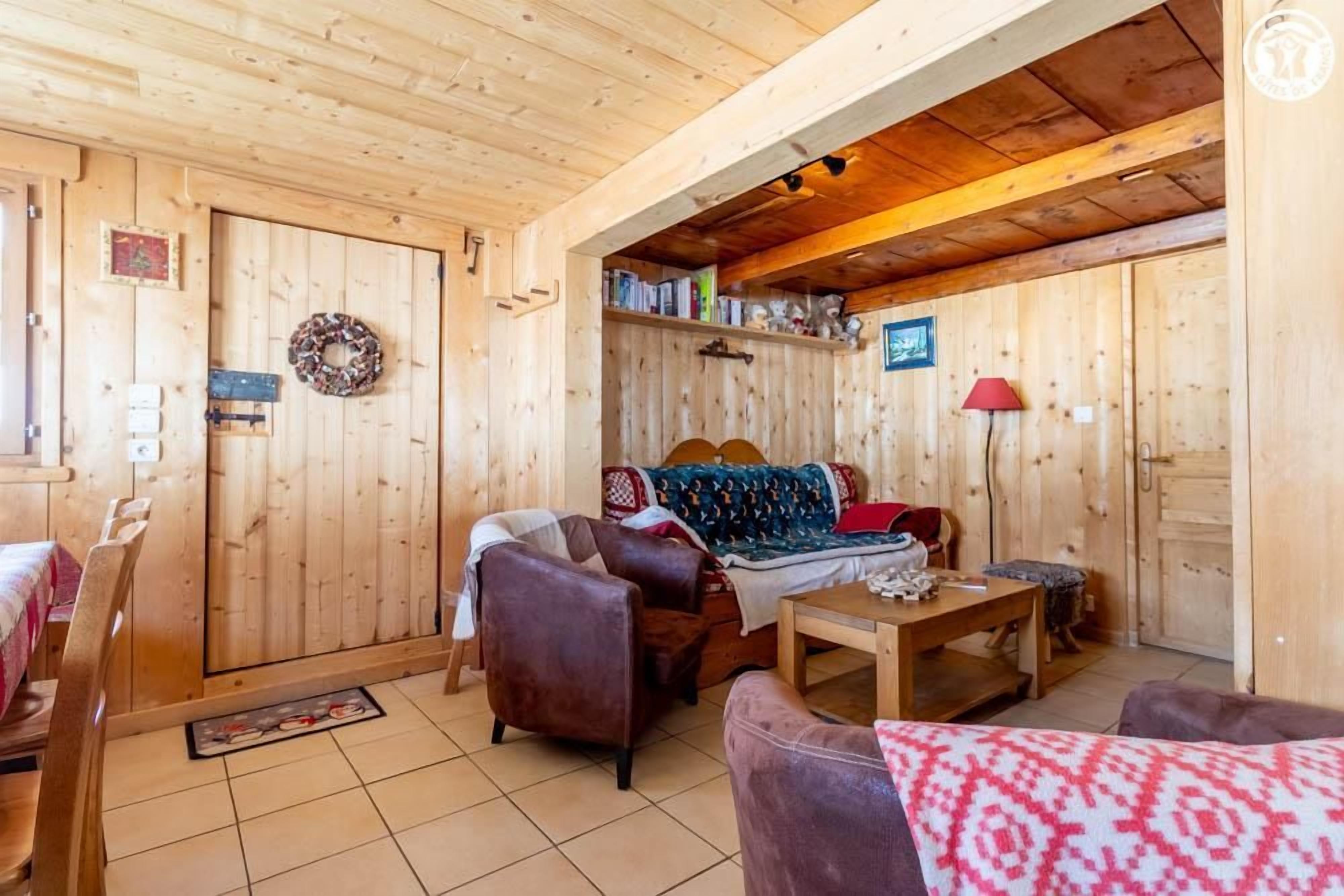 Een houten interieur met een bank, stoelen, een tafel en een deur versierd met een krans.