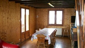 Una cabana de fusta amb taula de menjador, cadires i un sofà vermell.