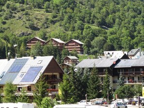 A hotel with multiple buildings, solar panels on the roof, and a mountainous backdrop. - LA RENOVEE - VALLOIRE (VALLOIRE)
