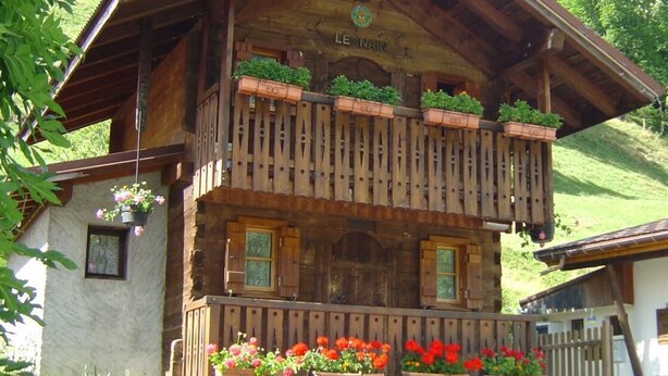 Un chalet en bois doté d’un balcon, de jardinières et d’une enseigne indiquant « LE NAIN ».