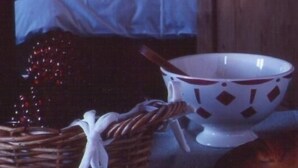 A wooden room with a bed, a nightstand, and a wicker basket.