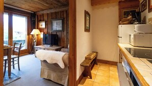 A cozy room with a bed, a desk, a television, and a kitchenette.