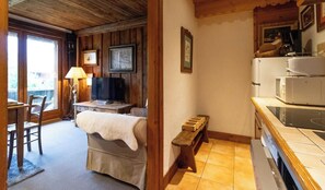 A cozy room with a bed, a desk, a television, and a kitchenette.
