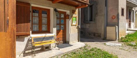 A building with a wooden balcony, a bench outside, and a sign indicating it's a gîte.