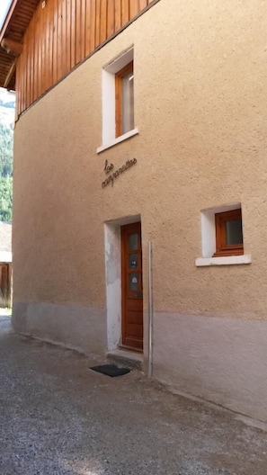 Ein Gebäude mit einer beigen Fassade, einer Holztür und einem kleinen Fenster.