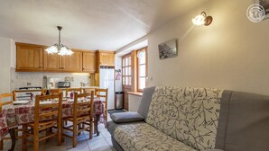 A cozy kitchen with wooden cabinets, a dining table set for four, and a sofa with a floral pattern. - LES CAMPANETTES 1st floor (PRALOGNAN LA VANOISE)