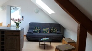 A cozy living room with a dark blue sofa, a small round coffee table, and a wooden cabinet. - ECOLE A GITER - LA GELINOTTE (SAINT FRANCOIS DE SALES)