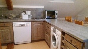 A compact kitchen with a dishwasher, washing machine, microwave, and coffee maker. - ECOLE A GITER - LA GELINOTTE (SAINT FRANCOIS DE SALES)
