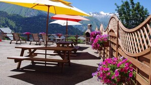 Outdoor seating with picnic tables and umbrellas, surrounded by wooden railings and flower baskets. - LE TALAPET - CONFETTI (ALBIEZ MONTROND)