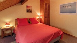 A bedroom with a bed, two bedside lamps, a nightstand, a wooden headboard, a framed picture on the wall, and a wooden ceiling. - LE TALAPET - CONFETTI (ALBIEZ MONTROND)