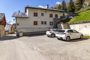 A building with a parking area, two white cars, and a mountainous backdrop. - LES JONQUILLES - VALLOIRE (VALLOIRE)