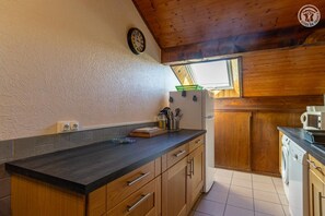 A kitchen with wooden cabinets, a black countertop, a clock, and a window.