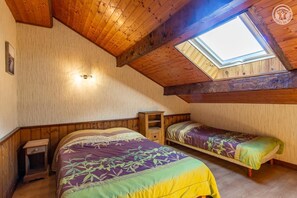 A bedroom with two beds, a skylight, wooden beams, and a nightstand. - LES JONQUILLES - VALLOIRE (VALLOIRE)