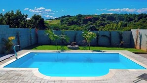 Une piscine rectangulaire à l’eau d’un bleu limpide, entourée d’une terrasse dallée.